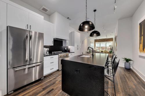a kitchen with white cabinets and a stainless steel refrigerator at Loft Style Spacious Lux Apt 102, Sleeps 6 in Atlanta