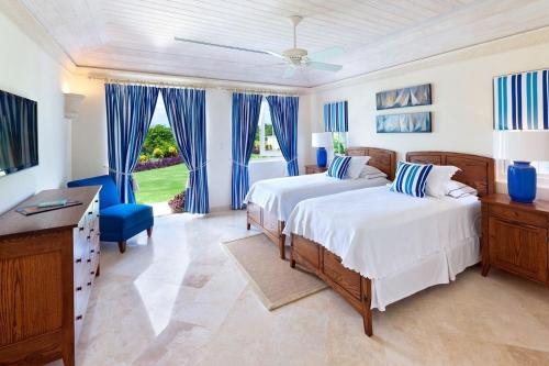 a bedroom with two beds with blue curtains and a desk at Royal Westmoreland - High Spirit by Blue Sky Luxury in Saint James