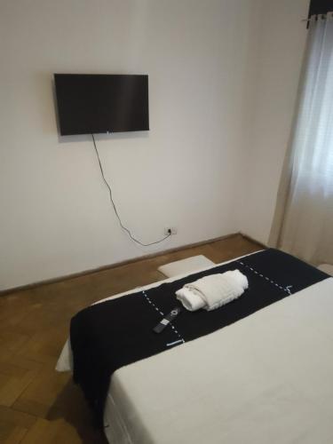 1 dormitorio con 1 cama y TV en la pared en El gallego en Concepción del Uruguay