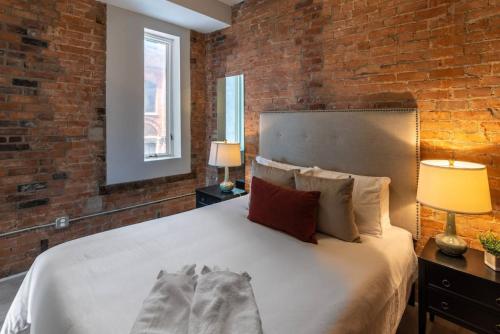 een slaapkamer met een groot bed met een bakstenen muur bij Rhinegeist next door - Free streetcar - Walk OTR in Cincinnati