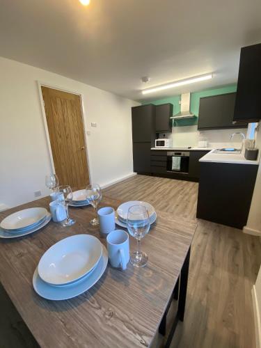 a table with plates and wine glasses on it in a kitchen at Modern Home with Free Parking Sleeps 6 in Leeds