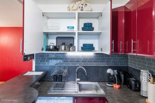 a kitchen with a sink and red cabinets at Cosy place for 4 - Fairytale Factory in Bussy-Saint-Georges