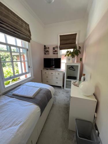1 dormitorio con cama, lavabo y ventana en The Victorian Rooms, en Surbiton