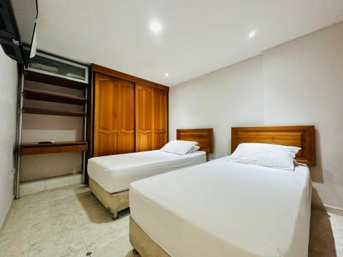 a hotel room with two beds and wooden cabinets at Apartamento Alvarez in Cartagena de Indias