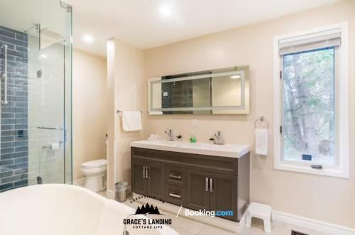 La salle de bains est pourvue d'un lavabo, de toilettes et d'un miroir. dans l'établissement Stunning All Season Waterfront Cottage By Grace's Landing Short Term Rental and & Long Term Accommodation Corbyville Ontario, à Belleville