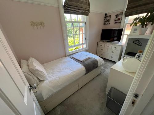 um pequeno quarto com uma cama e uma janela em The Victorian Rooms em Surbiton