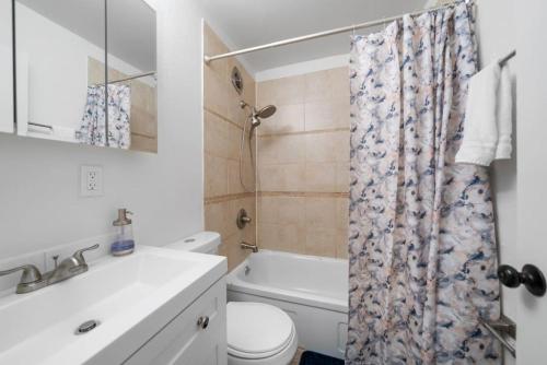 a bathroom with a toilet sink and a shower curtain at Cozy 1BR with Parking - Near UC, Zoo, Downtown in Cincinnati