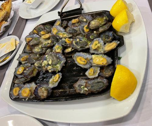 a plate of food with oysters and lemons on a table at Lua do Mar in Caniço