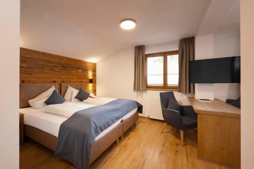 a hotel room with a bed and a desk at Hotel Brugger in Fulpmes