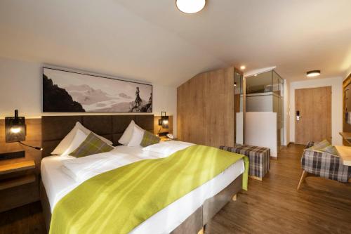 a bedroom with a large bed with a yellow and white blanket at Hotel Brugger in Fulpmes