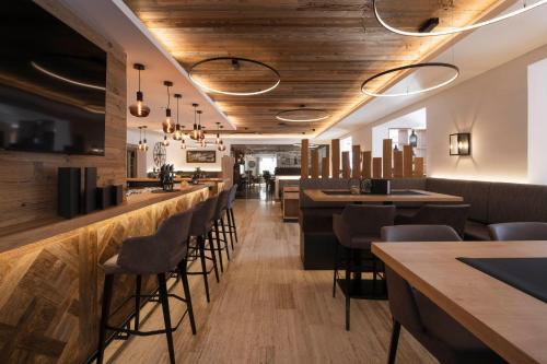 a restaurant with wooden ceilings and bar stools at Hotel Brugger in Fulpmes