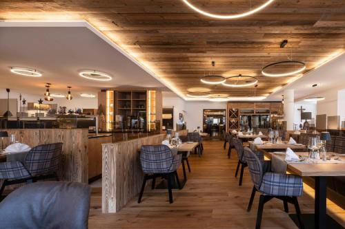 a restaurant with wooden ceilings and tables and chairs at Hotel Brugger in Fulpmes