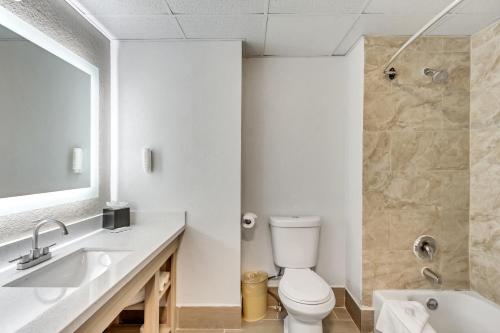 a bathroom with a toilet and a sink and a tub at Clarion Inn Salt Lake City Airport in Salt Lake City
