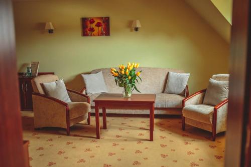 a living room with a couch and a table with flowers at Hotel Rycerski in Czeladź