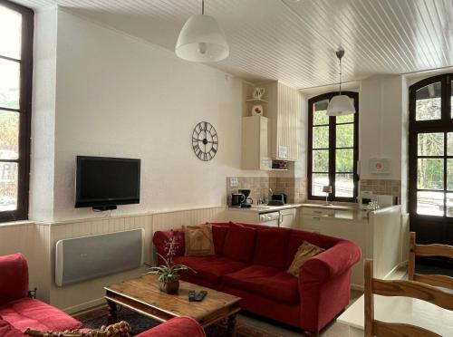 a living room with a red couch and a kitchen at La Source in Saint-Pierre-dʼArgençon