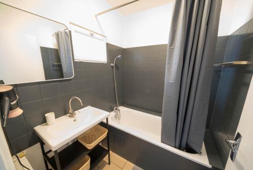 uma casa de banho com um lavatório, uma banheira e um chuveiro em AppartUnique - Chez Murillo em Vichy