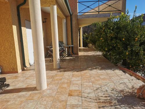 an outside walkway of a house with pillars and an orange tree at Chambre spacieuse avec bureau et balcon in Millas