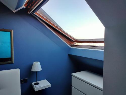 a room with a blue wall with a skylight at Mansarda DaSy in Ancona