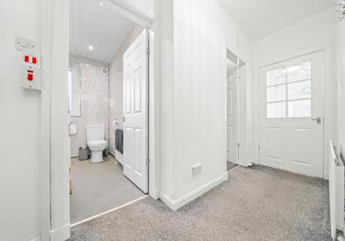 a white bathroom with a toilet and a door at Uddingston Apartment by Klass Living in Uddingston