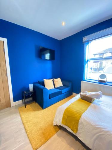 Habitación azul con cama y sofá en En-suite near Stratford in a guesthouse, en Londres