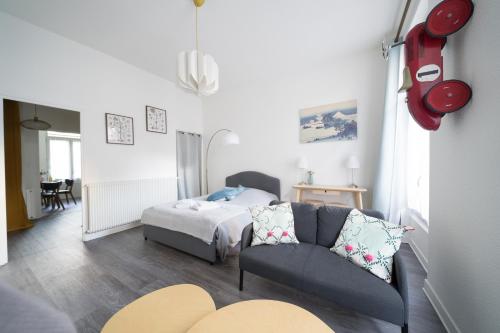 een woonkamer met een bank en een bed bij AppartUnique - Chez Murillo in Vichy