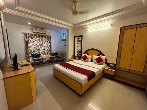 a hotel room with a large bed and a desk at Ganga Sagar Hotel in Bangalore