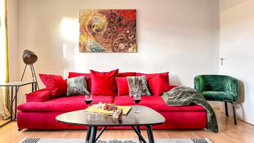 um sofá vermelho numa sala de estar com dois copos de vinho em Homestayplus Schwerin em Schwerin
