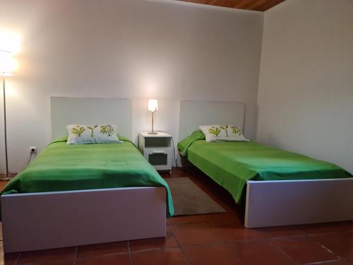 2 camas en una habitación con sábanas verdes en StoneWood Lodge AL, en São Vicente Ferreira