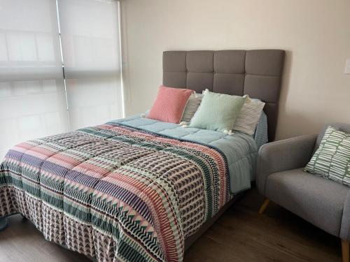 ein Bett mit einer bunten Decke und einem Stuhl in der Unterkunft Monterrico Polo Aparts - Cerca a la Embajada de USA in Lima
