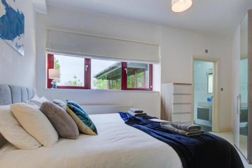 um quarto com uma cama branca com almofadas e uma janela em Open Mind Property - City Centre & Free Parking for Unlimited Vehicles em Fareham