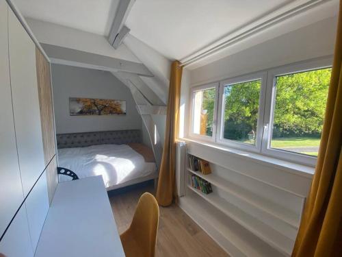 een kleine slaapkamer met een bed en een raam bij Le cottage des Vaux avec cheminée, sauna et jacuzzi dans un parc arboré in Senlisse