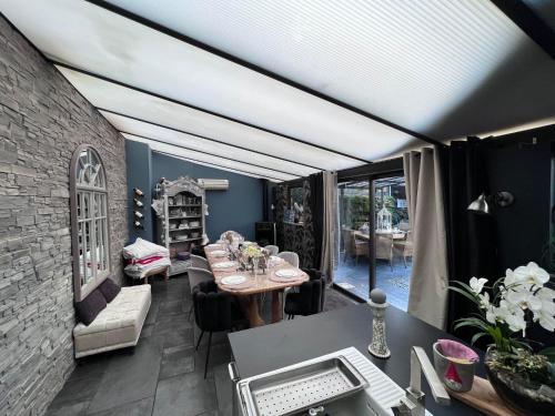 een woonkamer met een tafel en stoelen en een kamer met een plafond bij maison cosy et spa zen en Flandres et côte d'opale in Hondschoote