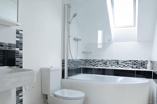 a bathroom with a tub and a toilet and a sink at Superb 4BD Stay in Wyton and Houghton Village in Wyton