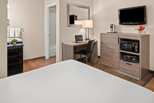 a hotel room with a bed and a desk with a television at Buck Meadows Lodge in Groveland