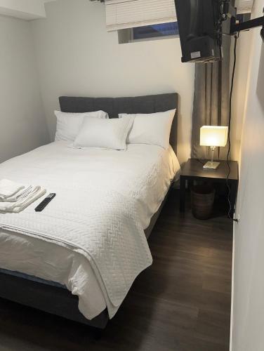 1 dormitorio con 1 cama con sábanas blancas y TV en Comfortable 3 Bed Basement Unit, en Winnipeg