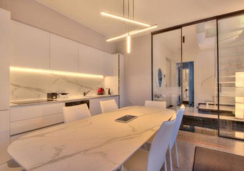 eine weiße Küche mit einem langen Tisch und weißen Stühlen in der Unterkunft Livin' Portofino LUX in Santa Margherita Ligure
