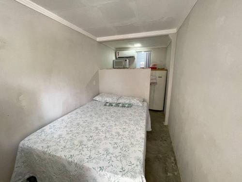 a small bedroom with a bed and a refrigerator at Quitinete da Nicole in Canindé de São Francisco