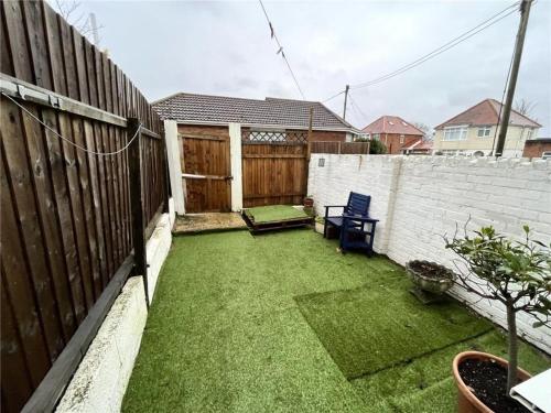 a small backyard with a fence and a chair at Central Location shops & beach in Milford on Sea