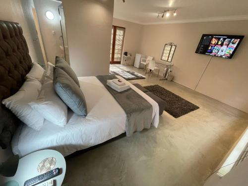 ein Schlafzimmer mit einem großen Bett und einem TV. in der Unterkunft Grants Hill Inn in Bloemfontein