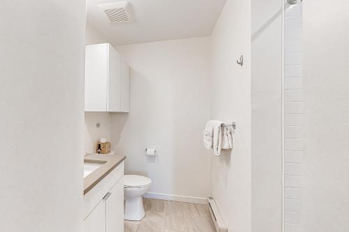 a white bathroom with a toilet and a shower at Mellow on Meadow Mile 2A in Fraser