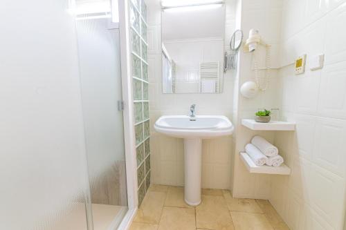 a white bathroom with a sink and a mirror at Hostal Ya in Aspe