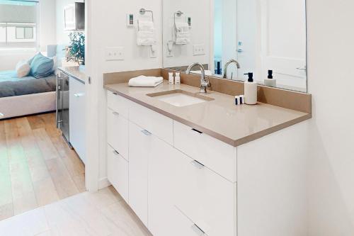 a white kitchen with a sink and a mirror at Mellow on Meadow Mile 2B in Fraser