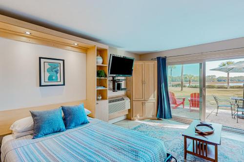 a bedroom with a bed and a tv and a patio at Bluff Villas 1799 in Hilton Head Island