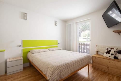 a bedroom with a bed with a green headboard at Casa Lucia Moena in Moena