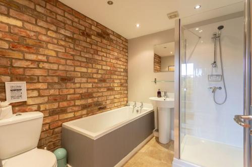 a bathroom with a brick wall and a tub and a sink at The Garden House in Low Catton 