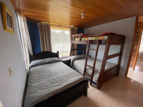 1 Schlafzimmer mit 2 Etagenbetten und 1 Bett in der Unterkunft Cabañas Villa del Dorado in Paipa