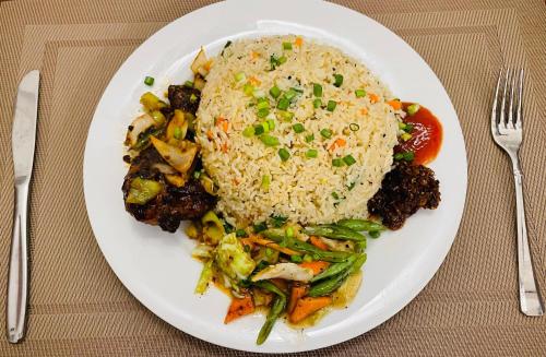 a white plate of food with rice and vegetables at Hotel Lake Park in Polonnaruwa