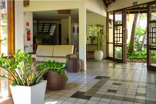 a lobby with potted plants on a tile floor at Arraial Bangalô Praia Hotel in Arraial d'Ajuda