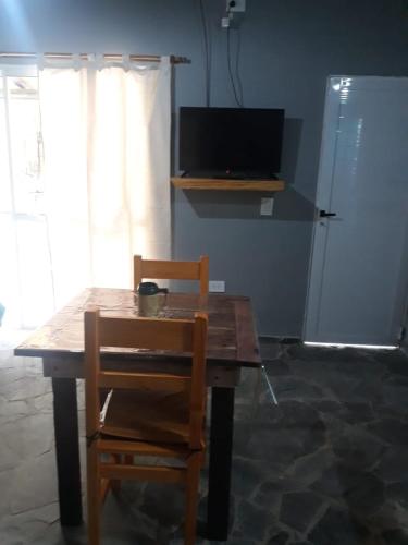a wooden table with two chairs and a television at La casita de Pablo in Santa Teresita