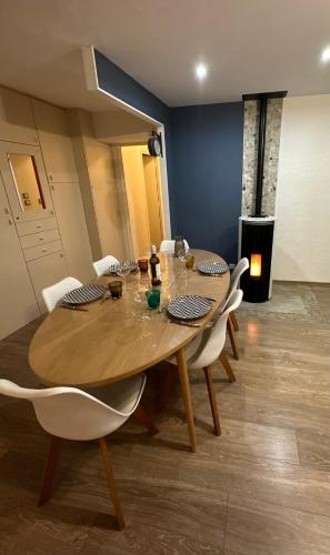 a dining room with a wooden table and white chairs at Appartement proche de centre ville in Rodez